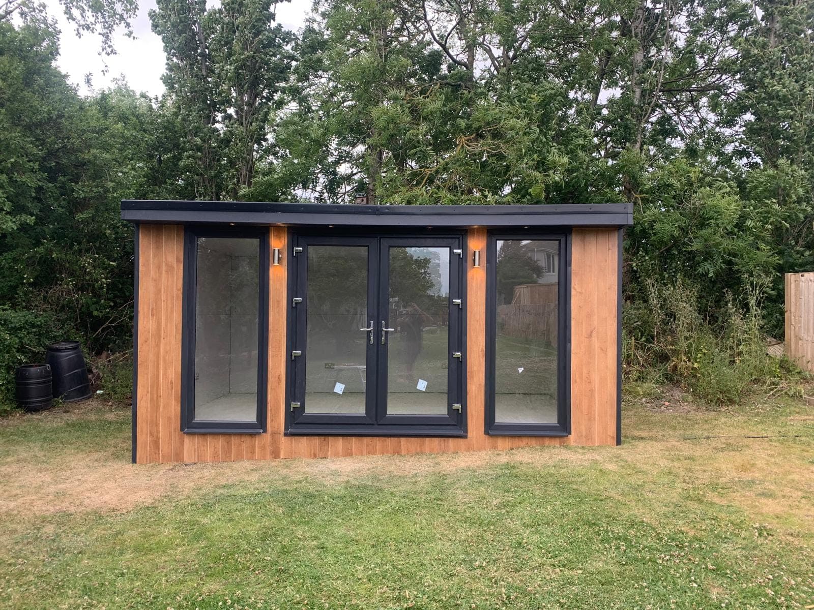 The front elevation of a timber-clad garden room with French doors and full-height side windows